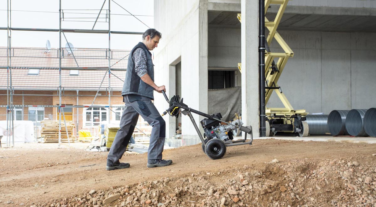 Profesjonalna  myjka wysokociśnieniowa HD 8/23 G Classic firmy Karcher z silnikiem spalinowym podczas transportu myjki pod górkę.